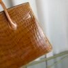 Miel Shiny Niloticus Crocodile Birkin 25 Retourne Gold Hardware Front view of a Birkin 25 bag in Miel shiny Niloticus crocodile leather with gold hardware.