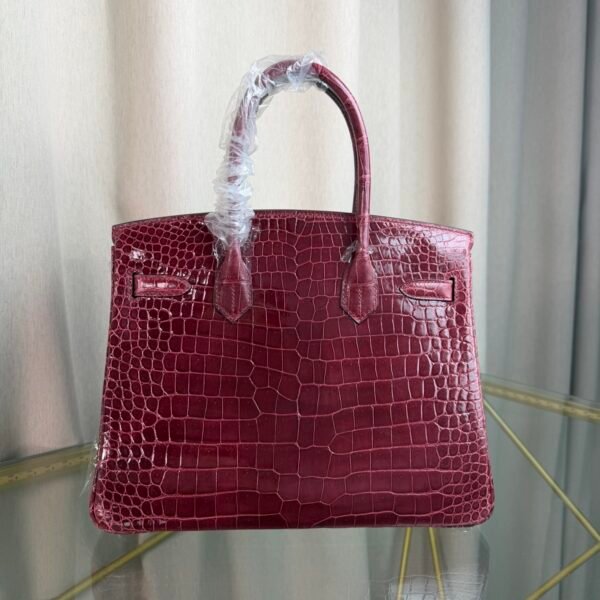 Bordeaux Shiny Niloticus Crocodile Birkin 30 Bag Front view of a luxury Birkin 30 bag in Bordeaux shiny Niloticus crocodile leather with gold hardware.