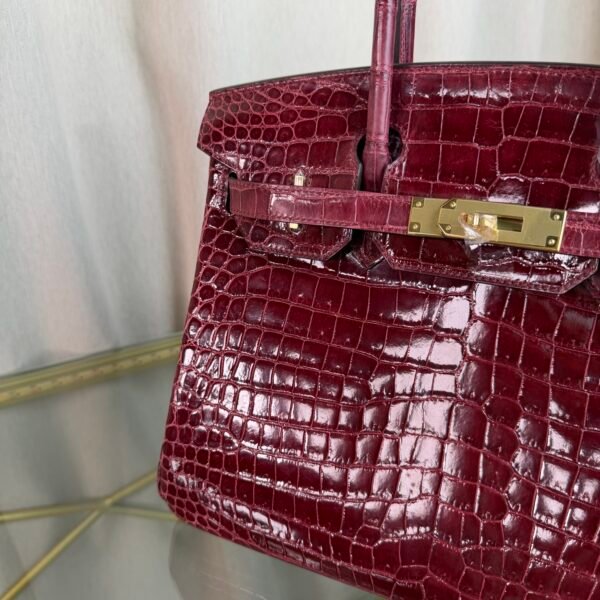 Bordeaux Shiny Niloticus Crocodile Birkin 30 Bag Front view of a luxury Birkin 30 bag in Bordeaux shiny Niloticus crocodile leather with gold hardware.