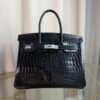 Black Shiny Niloticus Crocodile Birkin 30 Bag Front view of a luxury Birkin 30 bag in Black shiny Niloticus crocodile leather with palladium hardware.