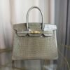 Gris Tourterelle Shiny Porosus Crocodile Birkin 30 Bag Front view of a luxury Birkin 30 bag in Gris Tourterelle shiny Porosus crocodile leather with gold hardware.